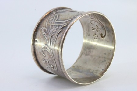 Argola de guardanapo em prata com motivos florais relevados envolvendo cartela para monograma.